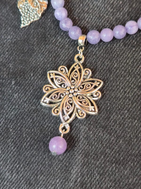 Close-up of compass charm on purple jade necklace