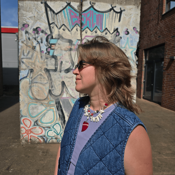 Model in sunglasses wearing necklace in front of Berlin graffiti wall