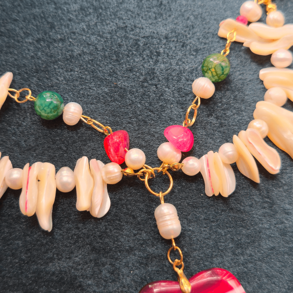 Detail of pearl, tourmaline, and red stone cluster near center of necklace