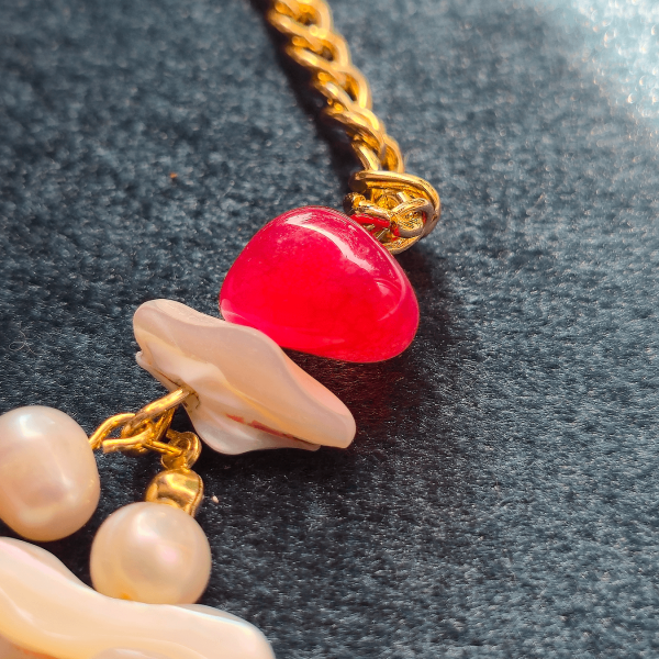 Red gemstone and shell accent near golden chain clasp